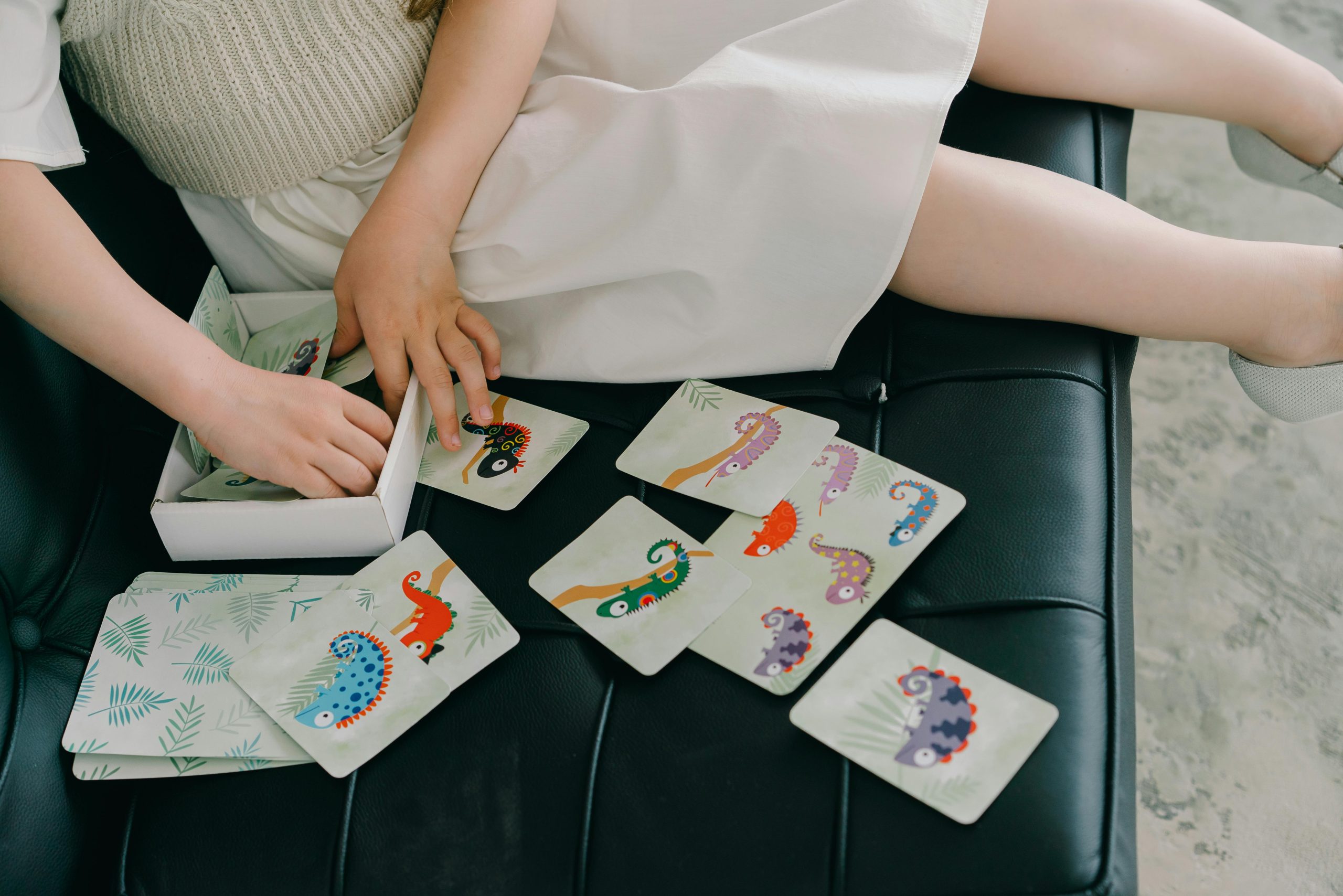 A child sitting on a couch playing with colorful educational animal cards indoors promoting learning and fun.
